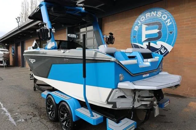 Slide: The Image of 2022 Nautique Super Air Nautique S23 boat in blue and white, parked outside a building. - 5