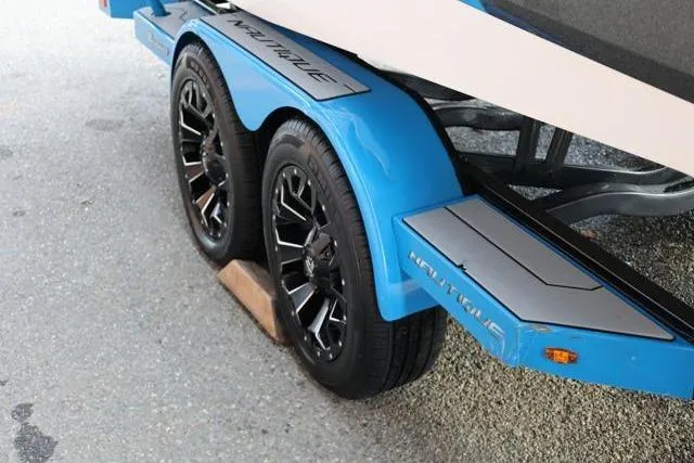 Slide: The Image of 2022 Nautique Super Air Nautique S23 trailer with blue fenders and black wheels. - 56