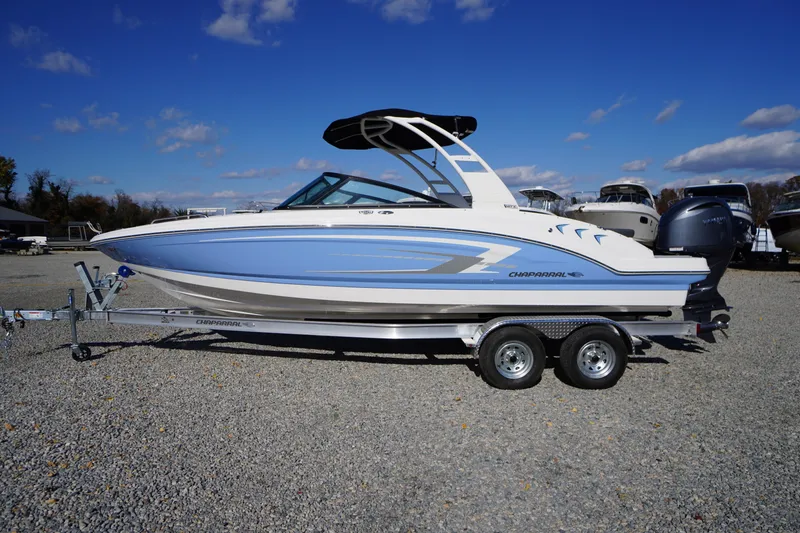 The Image of 2026 Chaparral 23 SSi OB boat on trailer, blue and white design, clear sky background. - 0