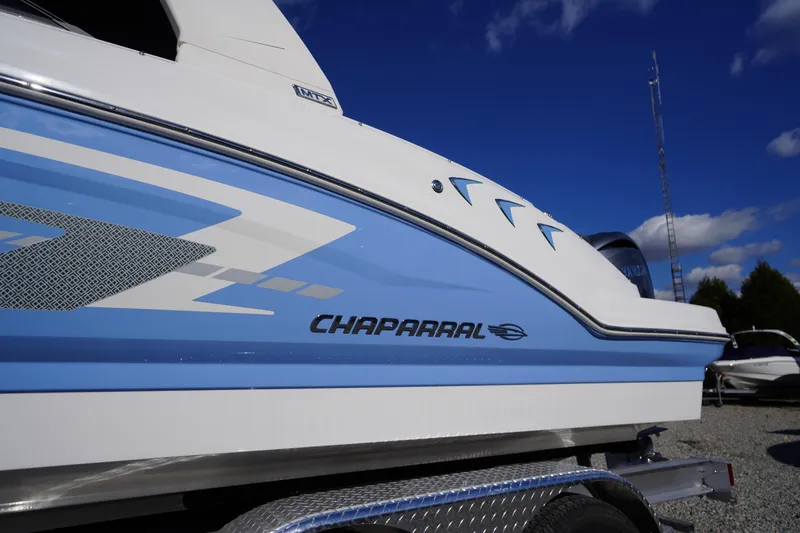 Slide: The Image of 2026 Chaparral 23 SSi OB boat side view with blue and white design. - 2