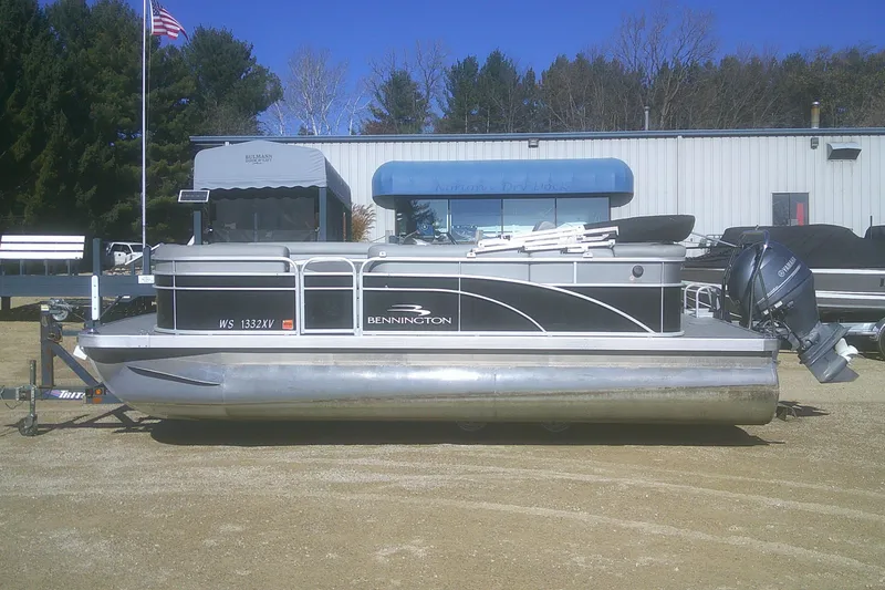 Slide: The Image of 2021 Bennington S 20 L-Bench pontoon boat with Yamaha outboard motor, parked outdoors. - 18