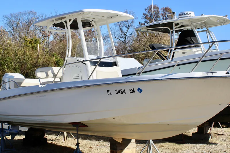 Slide: The Image of 2020 Boston Whaler 240 Dauntless boat on stands, outdoors, with trees in background. - 2