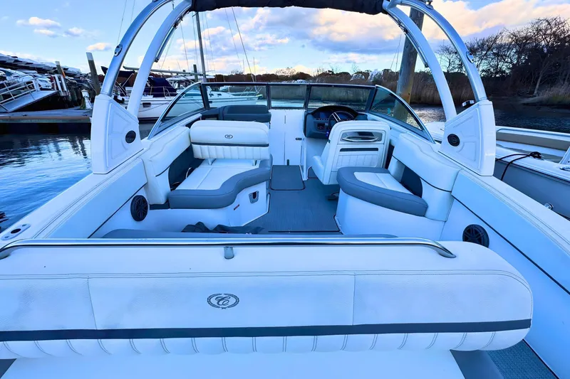 Slide: The Image of 2019 Cobalt 25SC boat interior with white seating and sleek design at a marina. - 10