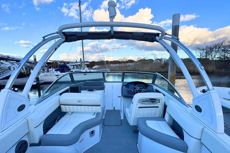 Slide: The Image of 2019 Cobalt 25SC boat interior with seating and steering, docked by the water. - 12