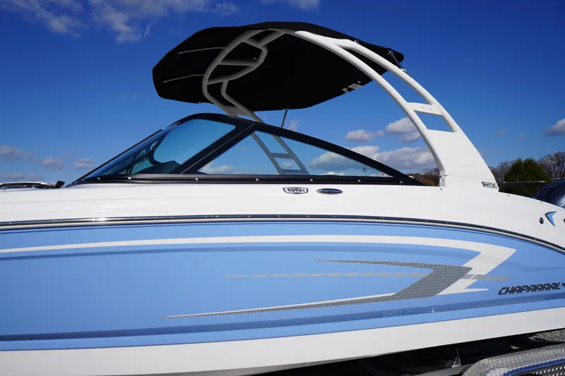 Slide: The Image of 2026 Chaparral 23 SSi OB boat with blue and white design under clear sky. - 1