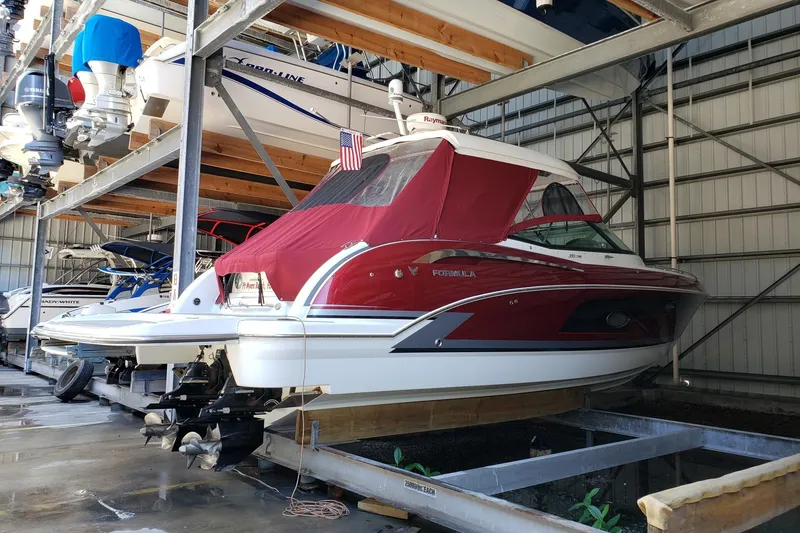 Slide: The Image of 2015 Formula 350 Crossover Bowrider in storage, red cover, American flag displayed. - 67
