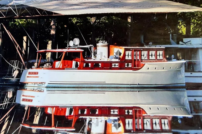 The Image of Classic 1930 47' ACF yacht docked, reflecting on calm water under a canopy. - 1