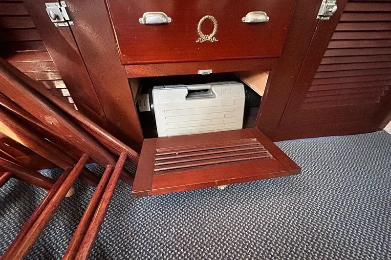 Slide: The Image of Wooden cabinet with open compartment, revealing a storage box inside, on a carpeted floor. - 10