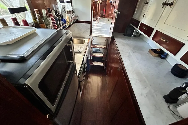 Slide: The Image of Galley kitchen in a 1930 Classic 47' ACF boat with modern appliances and wooden cabinetry. - 28