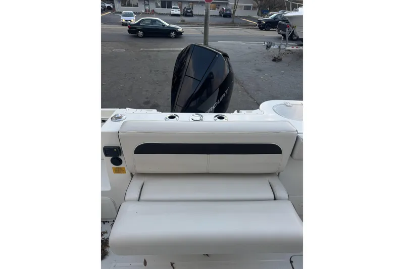 Slide: The Image of 2021 Sailfish 245DC boat with cushioned seating and outboard motor in a parking lot. - 10