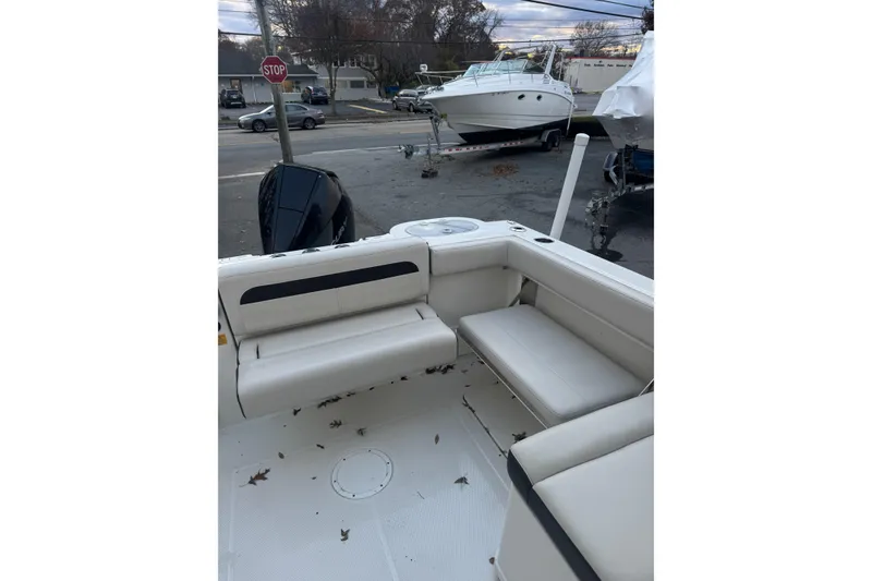 Slide: The Image of 2021 Sailfish 245DC boat interior with seating and outboard motor, parked near other boats. - 17