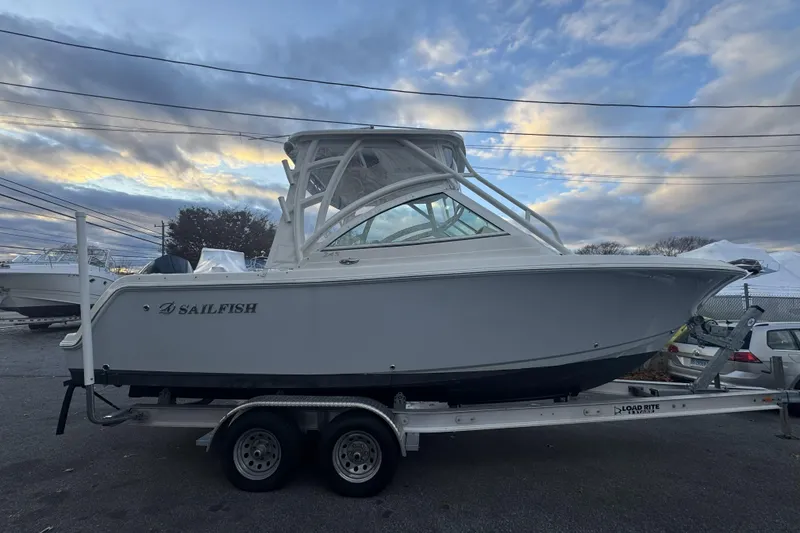 Slide: The Image of 2021 Sailfish 245DC boat on trailer under cloudy sky. - 2
