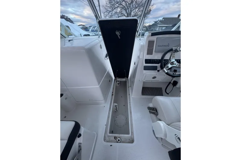 Slide: The Image of 2021 Sailfish 245DC boat interior with open storage compartment and Garmin navigation system. - 22