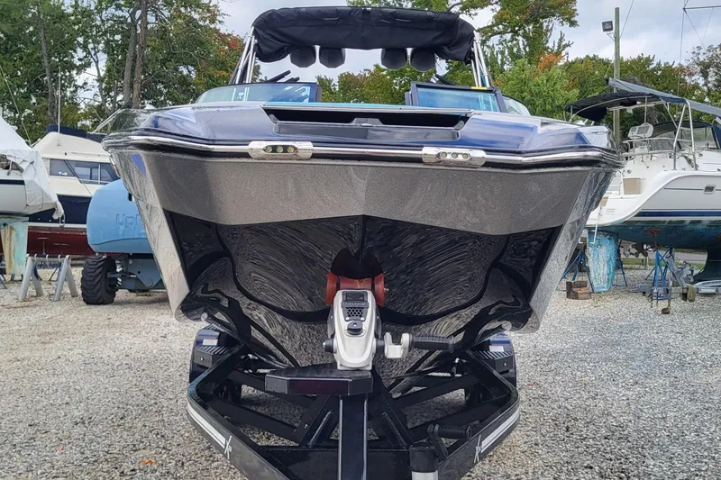 Slide: The Image of 2022 MasterCraft X24 boat on trailer, front view, in a marina setting. - 14