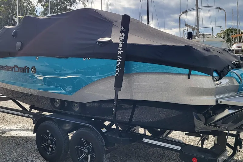 Slide: The Image of 2022 MasterCraft X24 boat with cover on trailer, parked outdoors. - 3