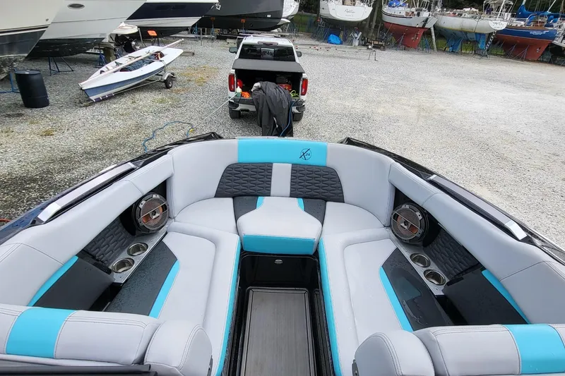 Slide: The Image of 2022 MasterCraft X24 boat interior with stylish seating and cup holders in a marina setting. - 5