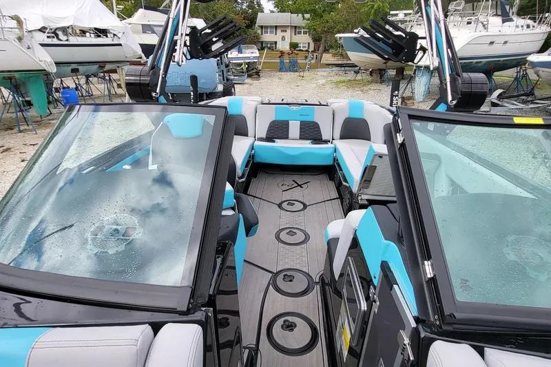 Slide: The Image of 2022 MasterCraft X24 boat interior with blue and gray seating, docked among other boats. - 6