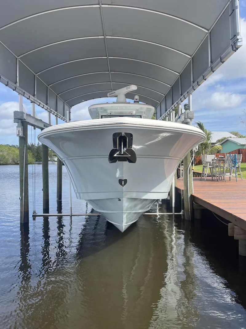 Slide: The Image of 2021 Sea Fox 368 Commander boat docked under a canopy on calm water. - 32