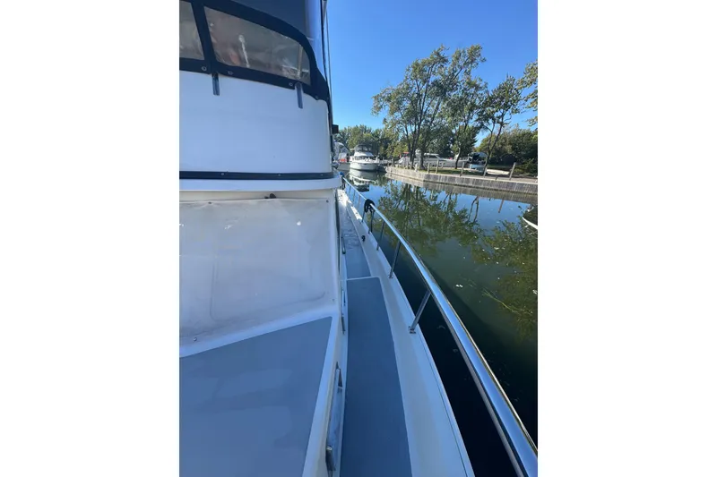 Slide: The Image of 2001 Monk Trawler boat docked by a calm waterway with trees in the background. - 27