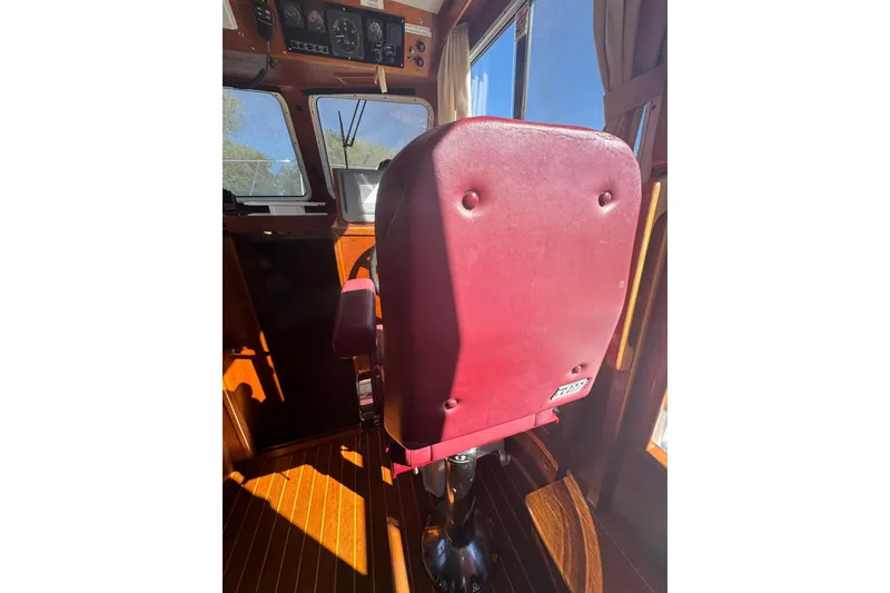 Slide: The Image of Captain's chair in 2001 Monk Trawler boat cockpit, featuring red upholstery and wooden interior. - 40