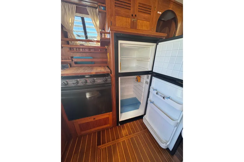 Slide: The Image of 2001 Monk Trawler kitchen with open fridge, stove, and wooden cabinetry. - 41
