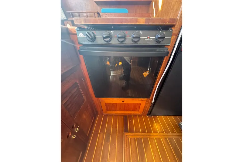 Slide: The Image of Wooden interior of 2001 Monk Trawler featuring a compact marine oven and stove. - 49