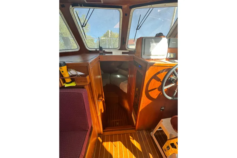 Slide: The Image of Interior of a 2001 Monk Trawler boat with wooden finishes and steering wheel. - 54