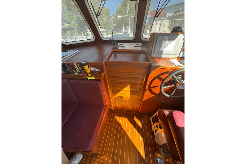 Slide: The Image of 2001 Monk Trawler interior with wooden helm, maroon seating, and navigation equipment. - 76