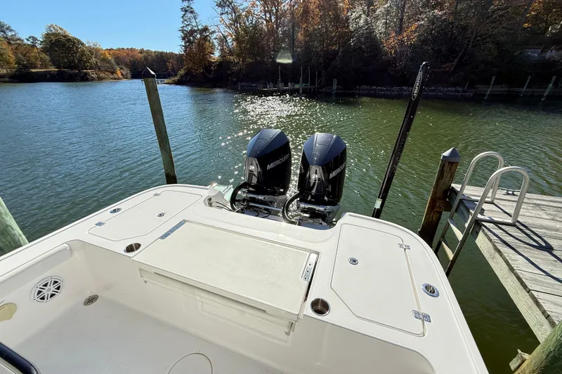 Slide: The Image of 2023 Caymas 281 HB boat with dual Mercury engines docked by a serene lake. - 18