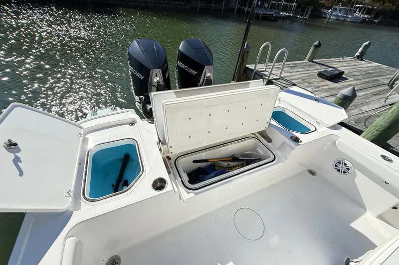 Slide: The Image of 2023 Caymas 281 HB boat with open storage compartments and dual Mercury engines. - 19