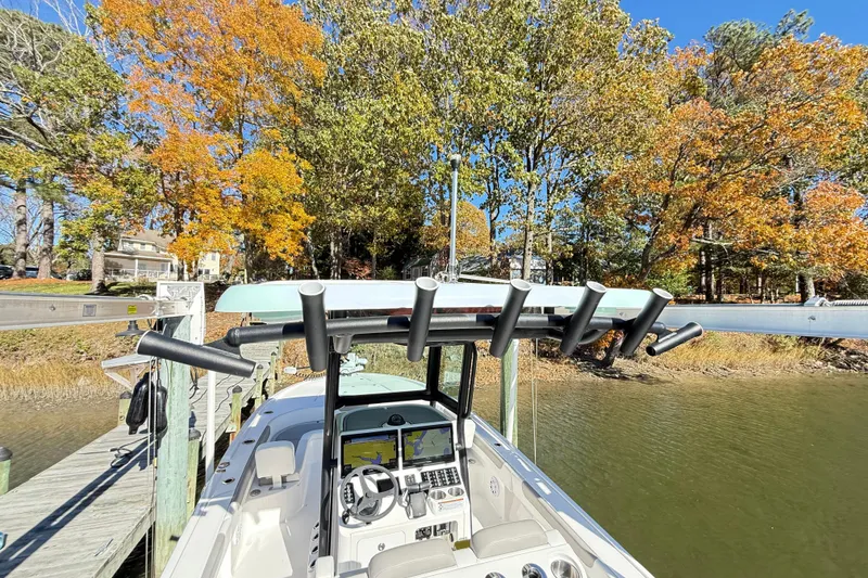 Slide: The Image of 2023 Caymas 281 HB boat docked by autumn trees, showcasing helm and rod holders. - 20