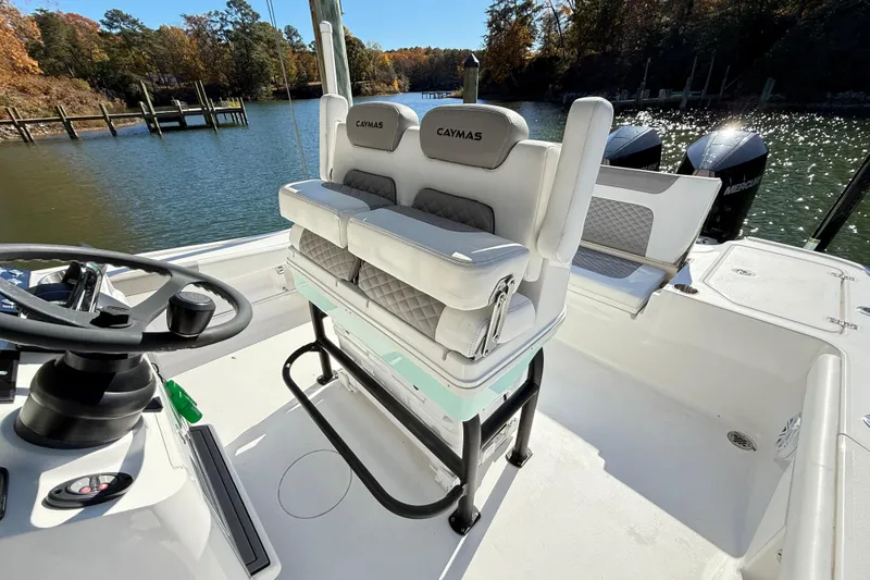 Slide: The Image of 2023 Caymas 281 HB boat interior with helm and seating, docked by a scenic lake. - 24