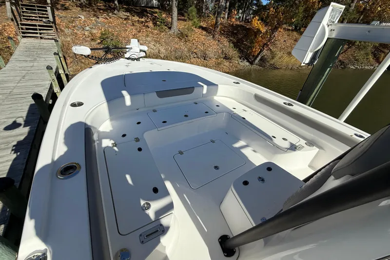 Slide: The Image of 2023 Caymas 281 HB boat deck with storage compartments, docked by a wooded shoreline. - 47