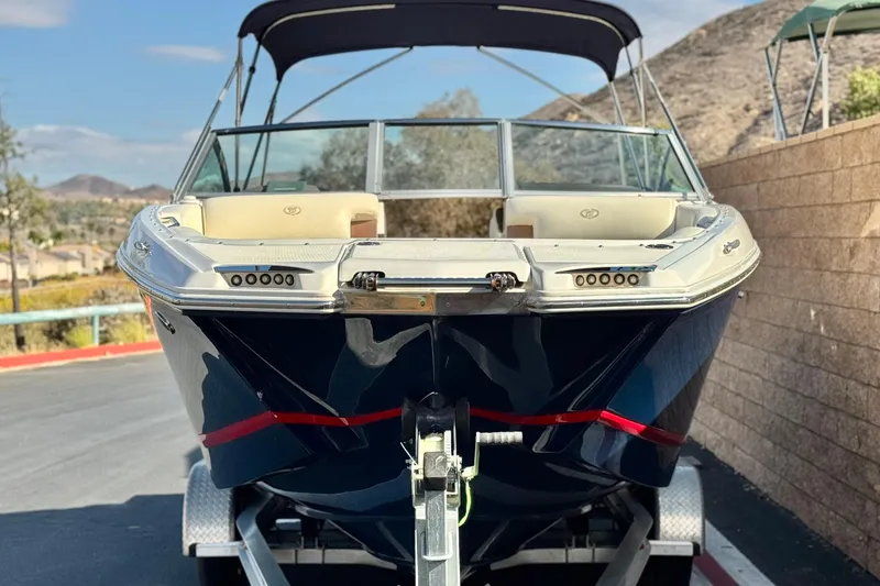 Slide: The Image of 2014 Cobalt 24SD boat on trailer, parked outdoors with scenic background. - 2
