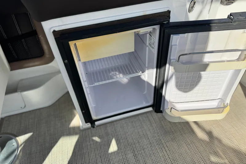 Slide: The Image of Open mini fridge on 2014 Cobalt 24SD boat, showing interior shelves. - 27