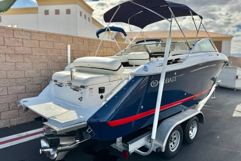 Slide: The Image of 2014 Cobalt 24SD boat on trailer, blue with red stripe, parked outdoors. - 5
