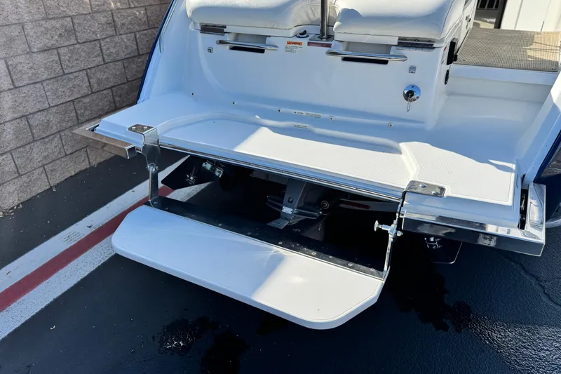 Slide: The Image of 2014 Cobalt 24SD boat swim platform with fold-down ladder, parked on asphalt. - 7