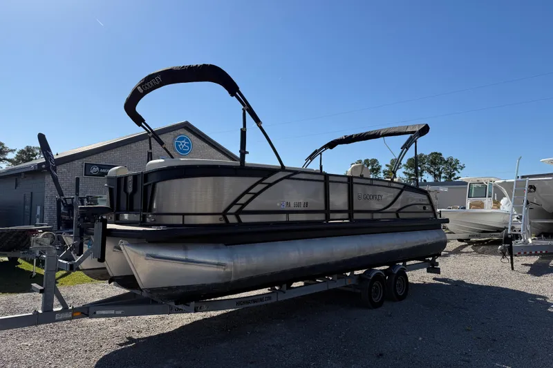The Image of 2022 Godfrey Monaco 255 SFL pontoon boat cruising on a serene lake. - 2