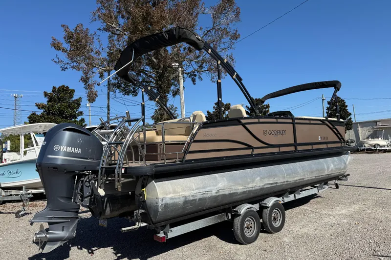 Slide: The Image of 2022 Godfrey Monaco 255 SFL pontoon boat cruising on a serene lake. - 8
