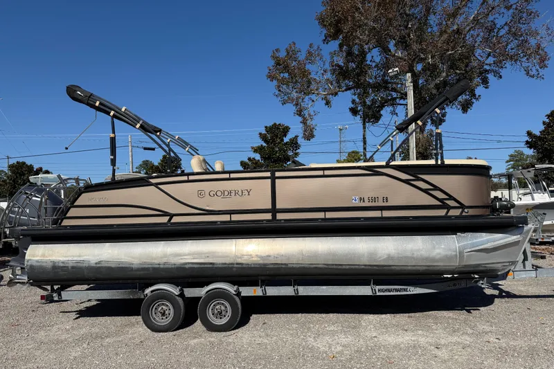 Slide: The Image of 2022 Godfrey Monaco 255 SFL pontoon boat cruising on a calm lake. - 9