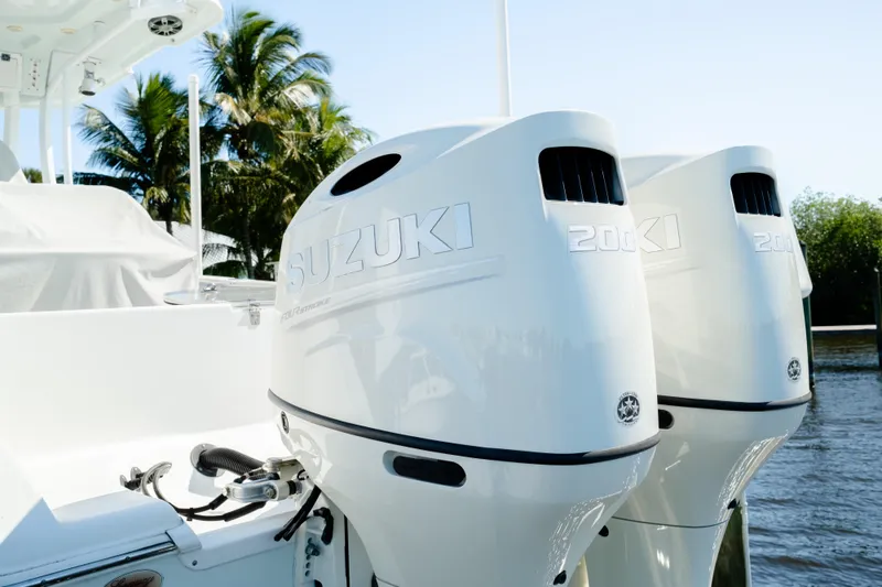 Slide: The Image of 2019 Sea Pro 259 Center Console with twin Suzuki 200 outboard engines, docked near palm trees. - 3