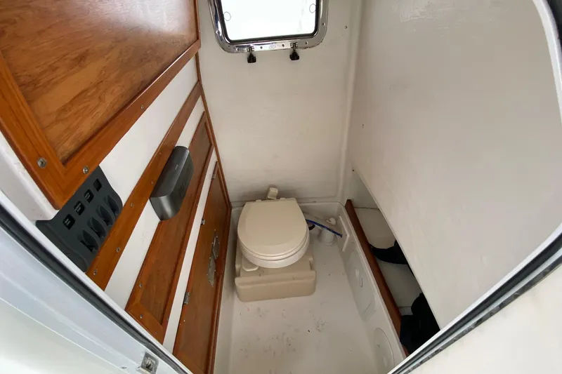 Slide: The Image of 2007 Roth Bilt 24 CC boat interior with compact marine toilet and wooden cabinetry. - 19