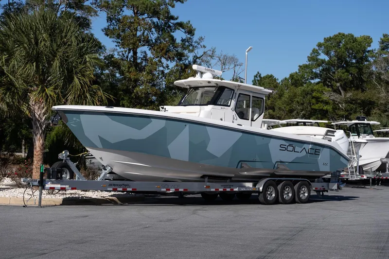 Slide: The Image of 2026 Solace 37 Pilot boat on trailer, parked outdoors with trees in background. - 2