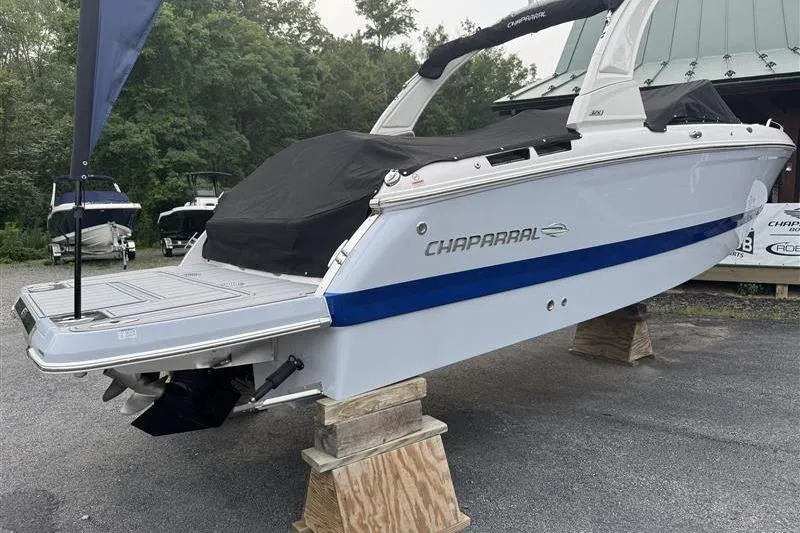 Slide: The Image of 2025 Chaparral 267 SSX boat on display, covered and elevated on wooden blocks. - 1