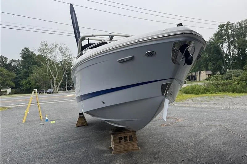 Slide: The Image of 2025 Chaparral 267 SSX boat on display, elevated on wooden blocks, outdoors. - 2