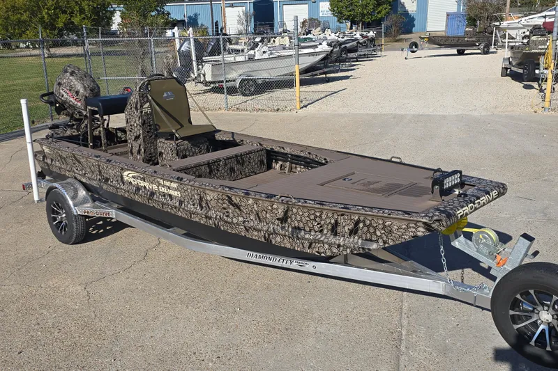 Slide: The Image of 2026 Pro-Drive 1856 SBX TD boat on trailer, camo design, parked outdoors. - 1