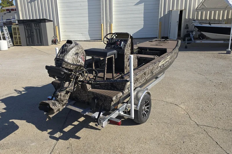 Slide: The Image of 2026 Pro-Drive 1856 SBX TD boat on trailer, camo design, parked outside a garage. - 4