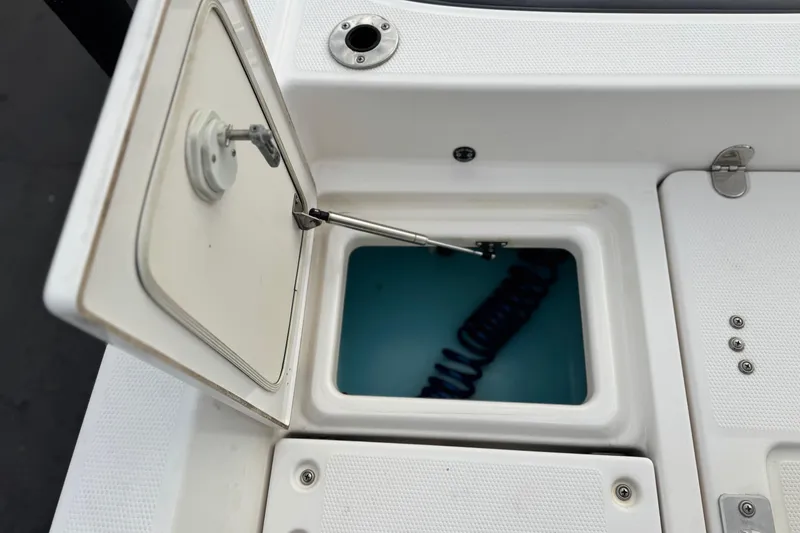 Slide: The Image of Open storage compartment on 2016 Yamaha Boats 190 FSH Deluxe, featuring a coiled hose. - 26