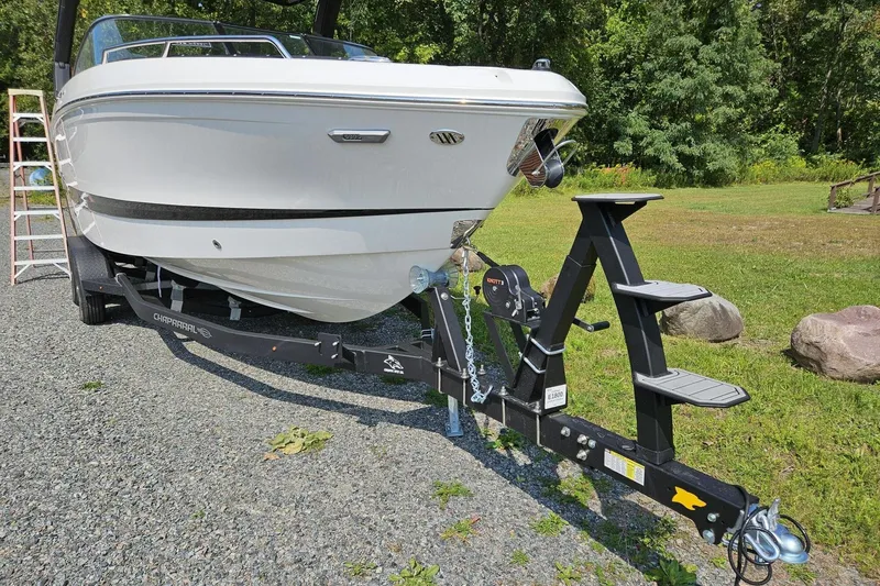 Slide: The Image of 2025 Chaparral 267 SSX boat on trailer, parked on gravel near grassy area. - 2