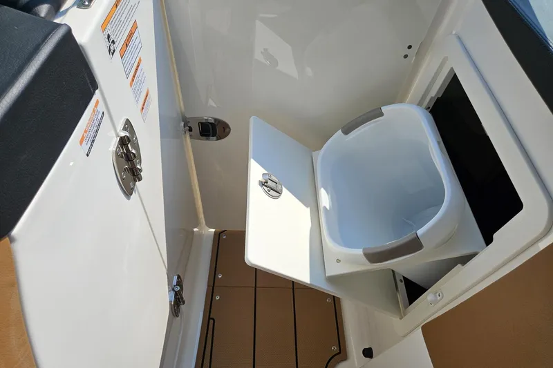 Slide: The Image of 2025 Chaparral 267 SSX boat interior with built-in storage compartment and bucket. - 21